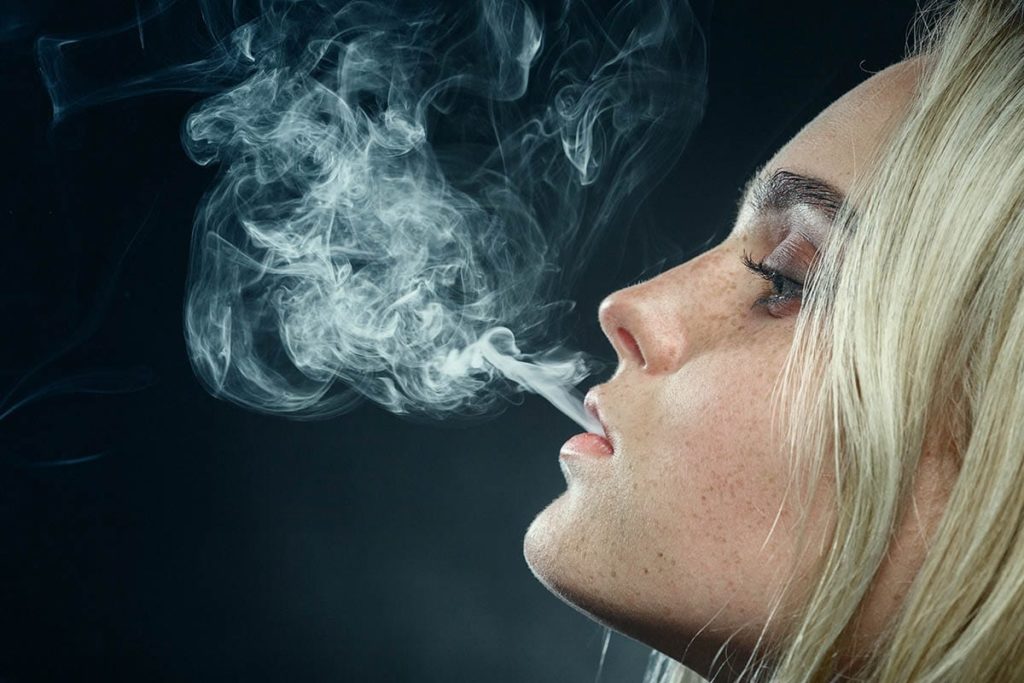 woman exhaling smoke while smoking marijuana