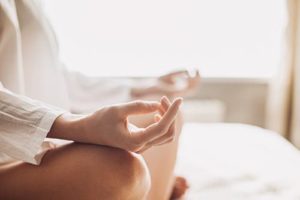 person sitting with crossed legs and palms upward practicing meditation therapy