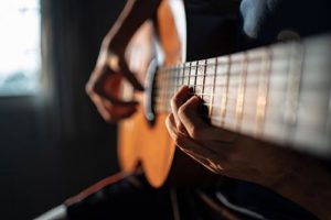 person playing guitar as music therapy for addiction recovery