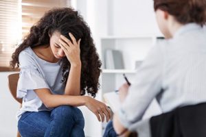 troubled young woman with head in her hand with therapist during a trauma therapy session