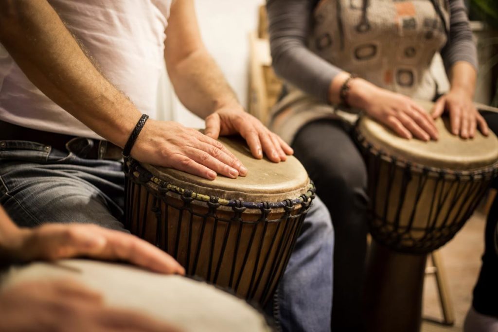 group of people playing drums in a drumming circle as part of the 5 benefits of music therapy