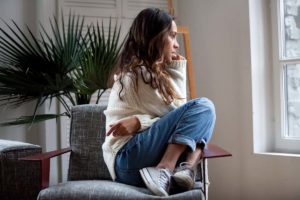 agitated woman sitting awkwardly in chair displaying the 5 common signs of anxiety