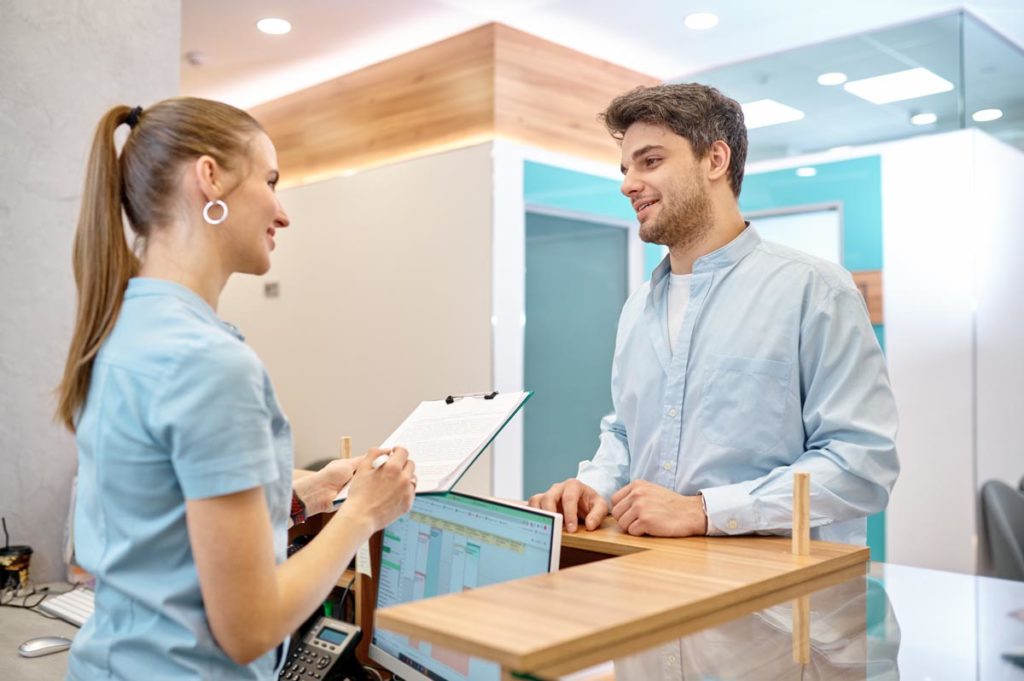 Patient talking to health professional at desk at inpatient rehab