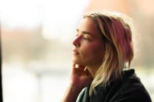 Woman with hand to face, pondering relapse