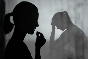 silhouette of a woman about to take a pill with a silhouette of same woman in the background with her head in her hands wondering how to prevent prescription drug addiction