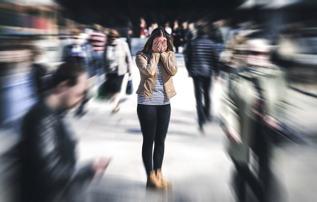 blurred image of distraught woman surrounded by crowd symbolizing what are the common causes of anxiety