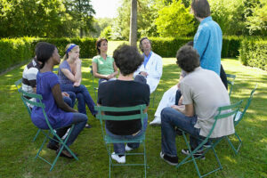 group of men and women seated outside in a group therapy session as part of an alcohol detox center program