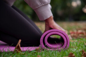 a woman using yoga therapy for addiction recovery rolls out her yoga mat