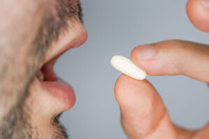 close up image of man about to swallow a pain pill and discover can you become addicted to painkiller meds