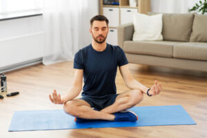 young man seated in meditative yoga pose and discovering is meditation helpful as a therapy for addiction treatment.