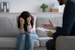 a person holds their head while a therapist in a depression treatment program talks