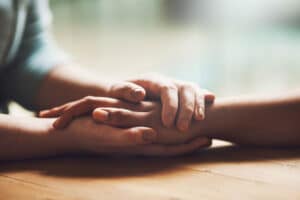 a person holds another's hand after explaining how to calm ptsd triggers