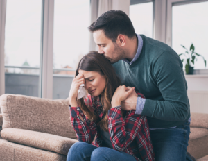 man hugging and consoling his distraught wife after discovering signs your loved one has bipolar disorder