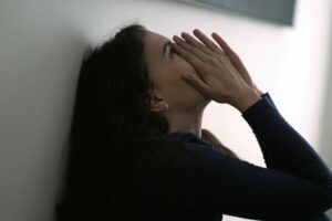 distraught woman leaning against wall and wondering when is it time to go to drug rehab?