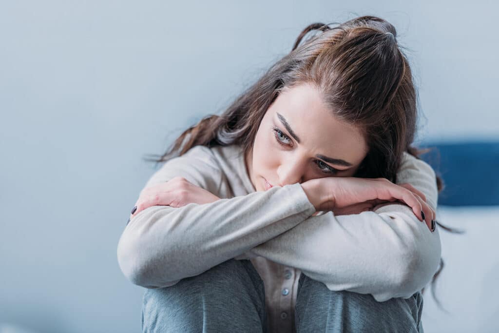 young woman struggling with depression contemplating the importance of understanding the types of depression